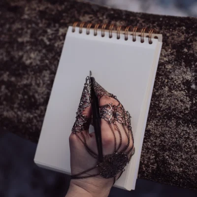 kontakt-fantasy-autorin-schreibt-notizbuch Hand einer Fantasy-Autorin schreibt in ein Notizbuch