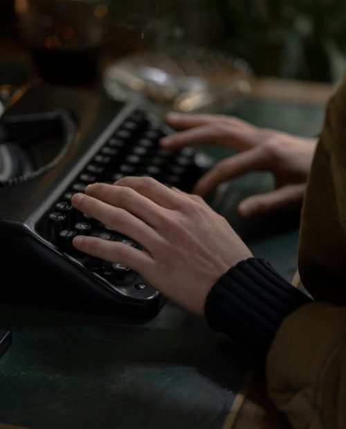 Hände einer Fantasy-Autorin beim Schreiben an einer Schreibmaschine